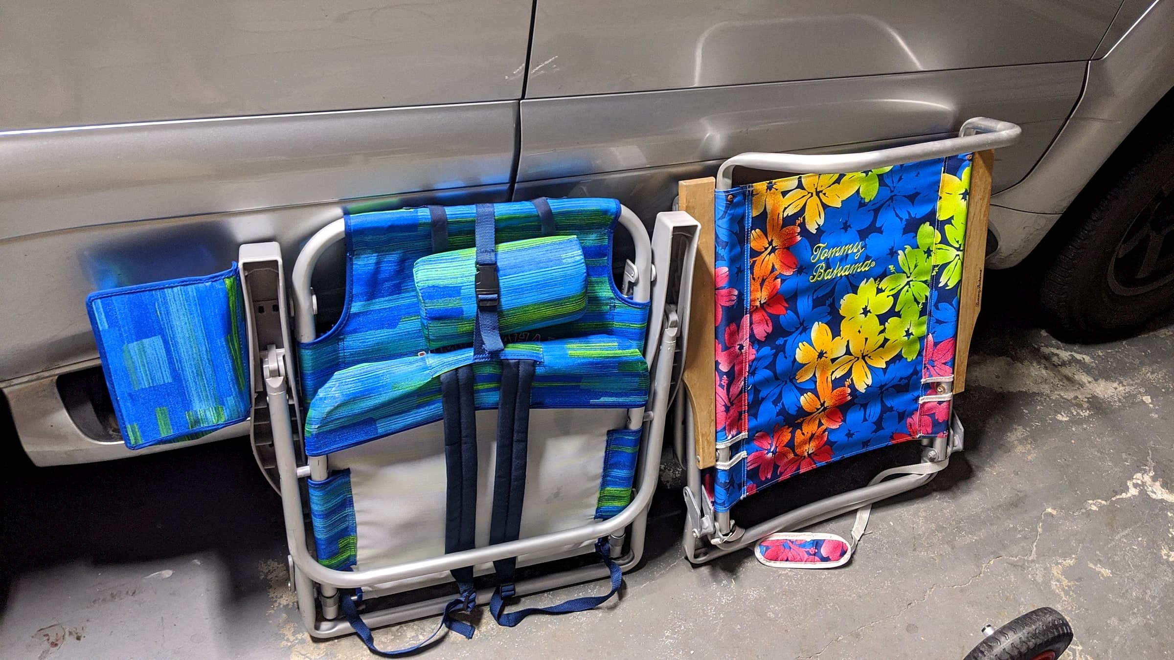 Two folded Tommy Bahama backpack beach chairs loaded in the bed of a truck