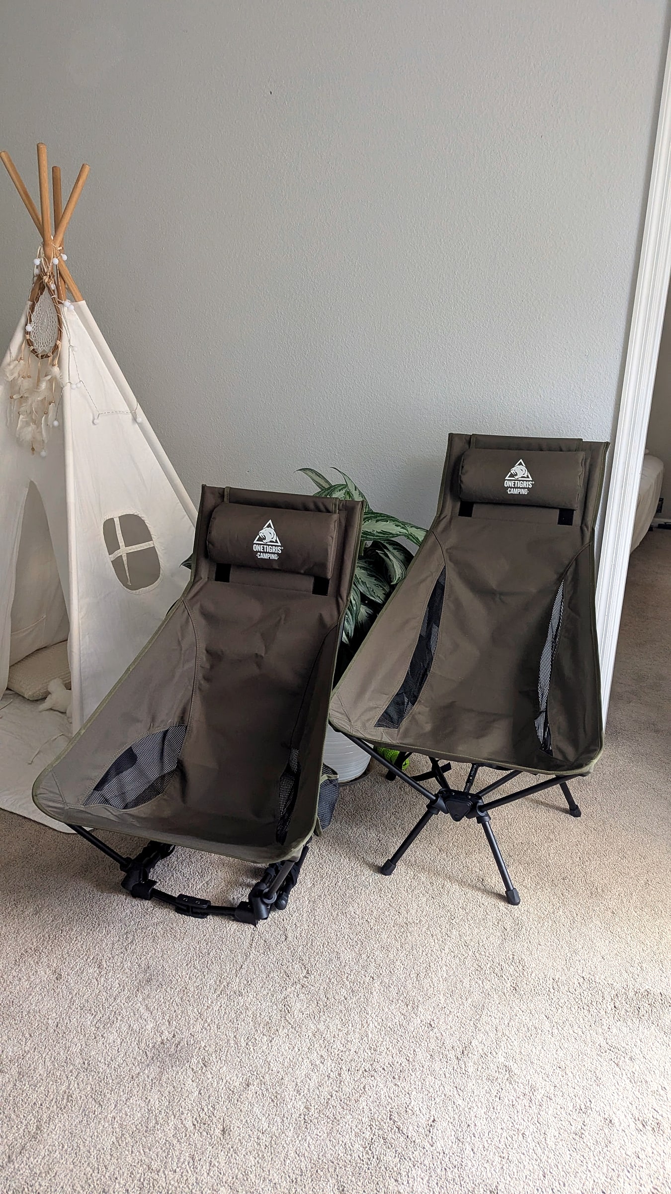 Two folded OneTigris ultralight camping chairs with headrests, set up indoors before a trip
