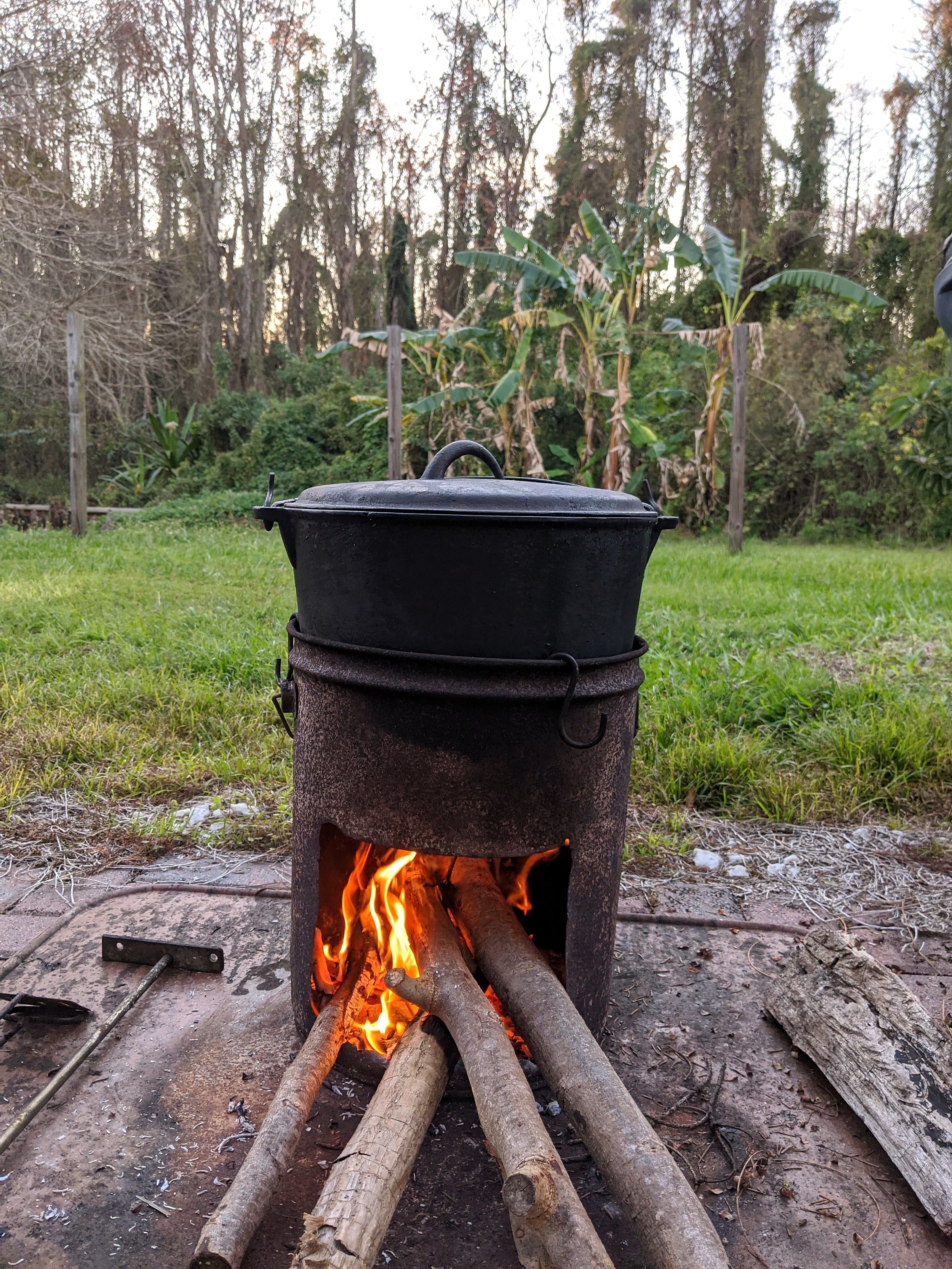 A pot cooking over a wood-fired rocket stove outdoors