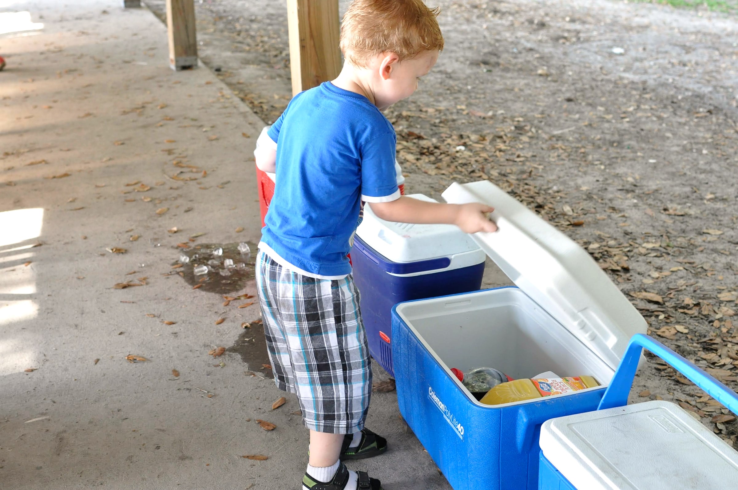 A child standing next to two coolers at a campsite