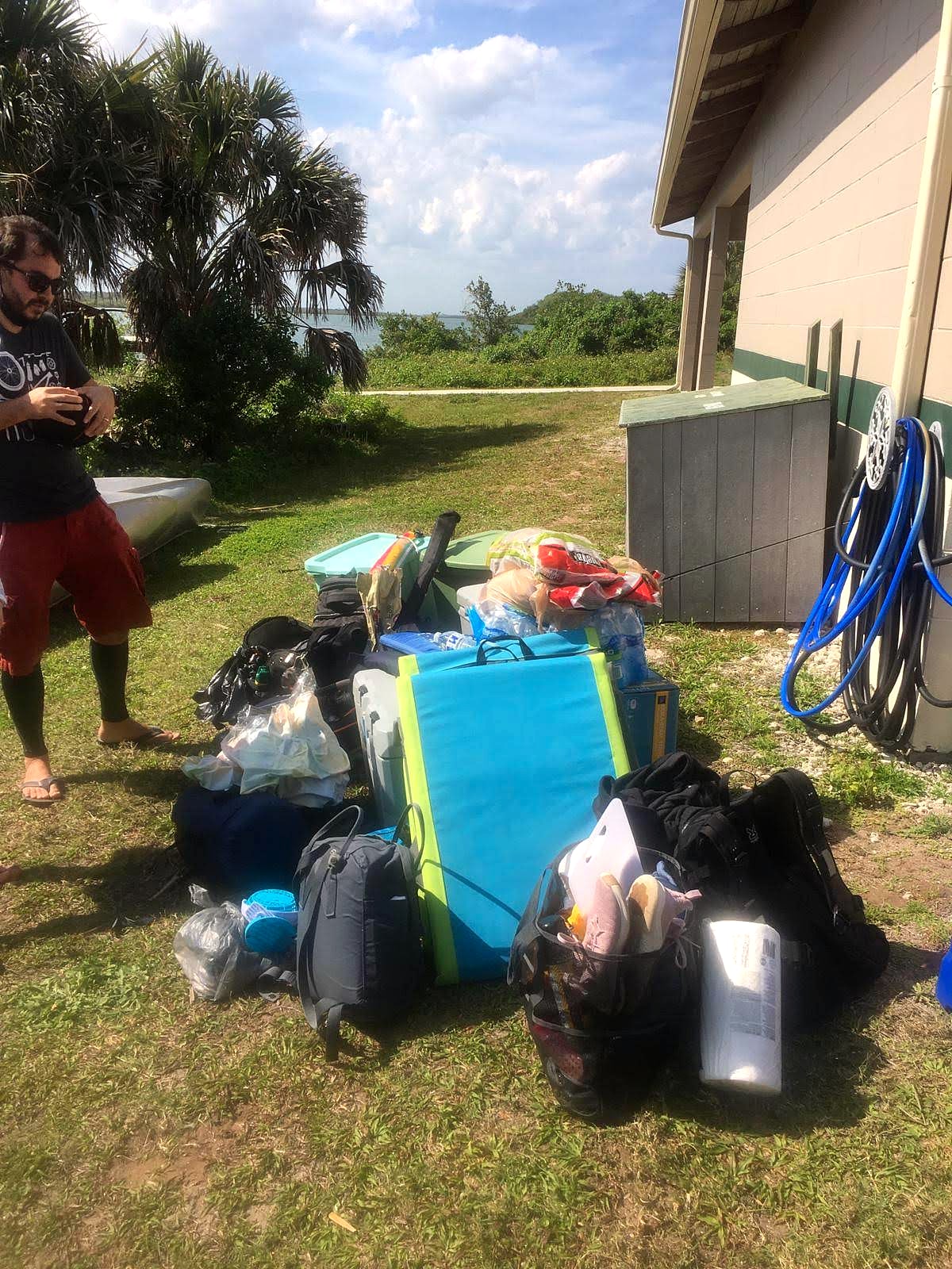 A pile of camping gear staged in a garage after a trip, waiting to be sorted back into storage bins